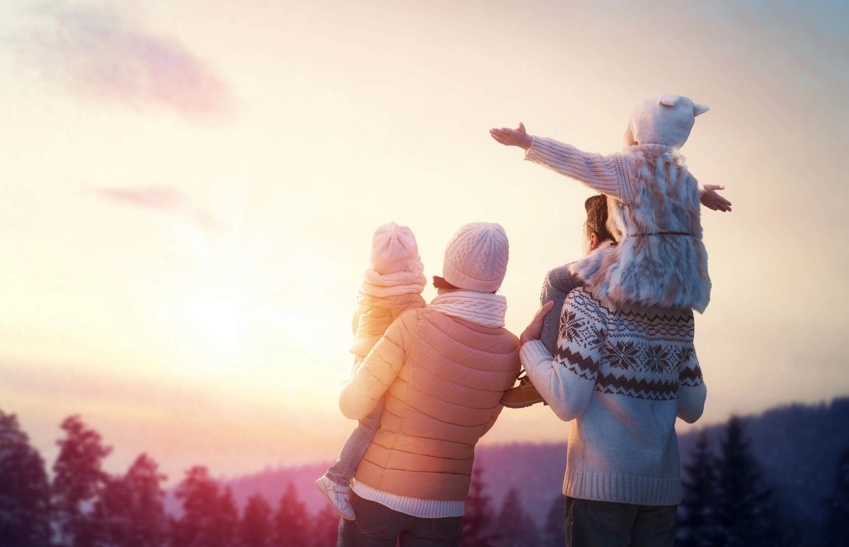 Jak witamina D wpływa na organizm? Rodzice z dwójką dzieci podziwiają zimową scenerię w górach.