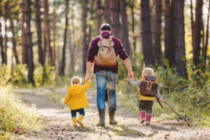 5 składników na odporność organizmu. Tata z dwójką dzieci spaceruje po lesie.