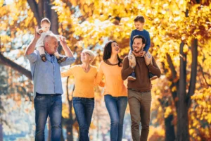 Sposoby na odporność - jak zwiększyć odporność organizmu? Szczęśliwa rodzina - mama, tata, dzieci i dziadkowie - spacerują po jesiennym parku.