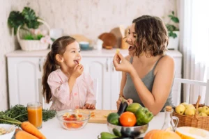Mama z córeczką przygotowują w kuchni zdrowy posiłek na bazie warzyw, bogaty w witaminy ważne dla dzieci oraz cenne składniki odżywcze.